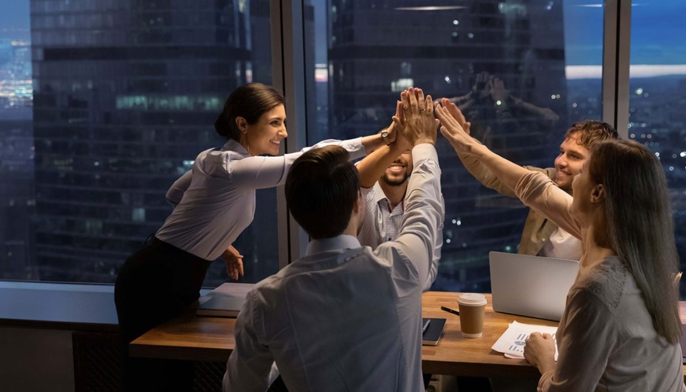 Équipe en réunion autour d’une consultante présentant des tableaux de bord et indicateurs produits, illustrant un accompagnement en conseil product management axé sur la collaboration, la prise de décision et la stratégie.